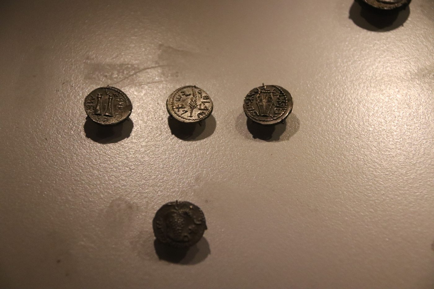 Several bronze Bar Kokhba revolt coins on a museum display surface