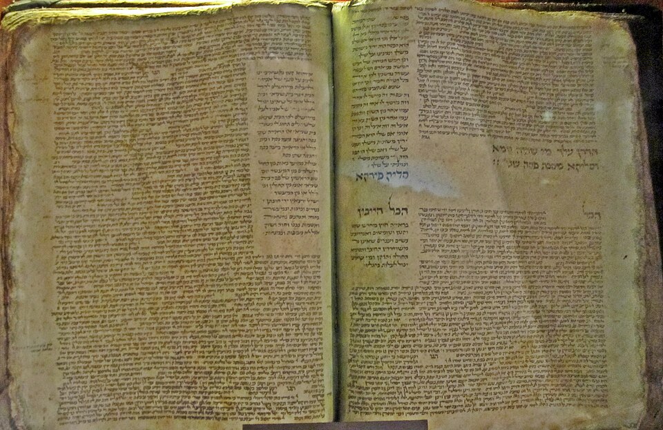 An open medieval Babylonian Talmud manuscript, hand-copied in 14th-century France, its parchment leaves covered in dense Hebrew script